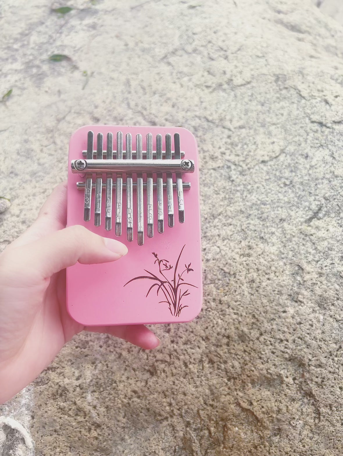 Video preview of hand playing pink 10 key kalimba being played, showcasing easy instrument sound and design